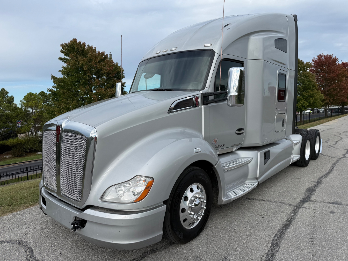 Kenworth T680 sleeper tractor in silver, front three-quarter view showing grille, hood, and side fuel tanks.