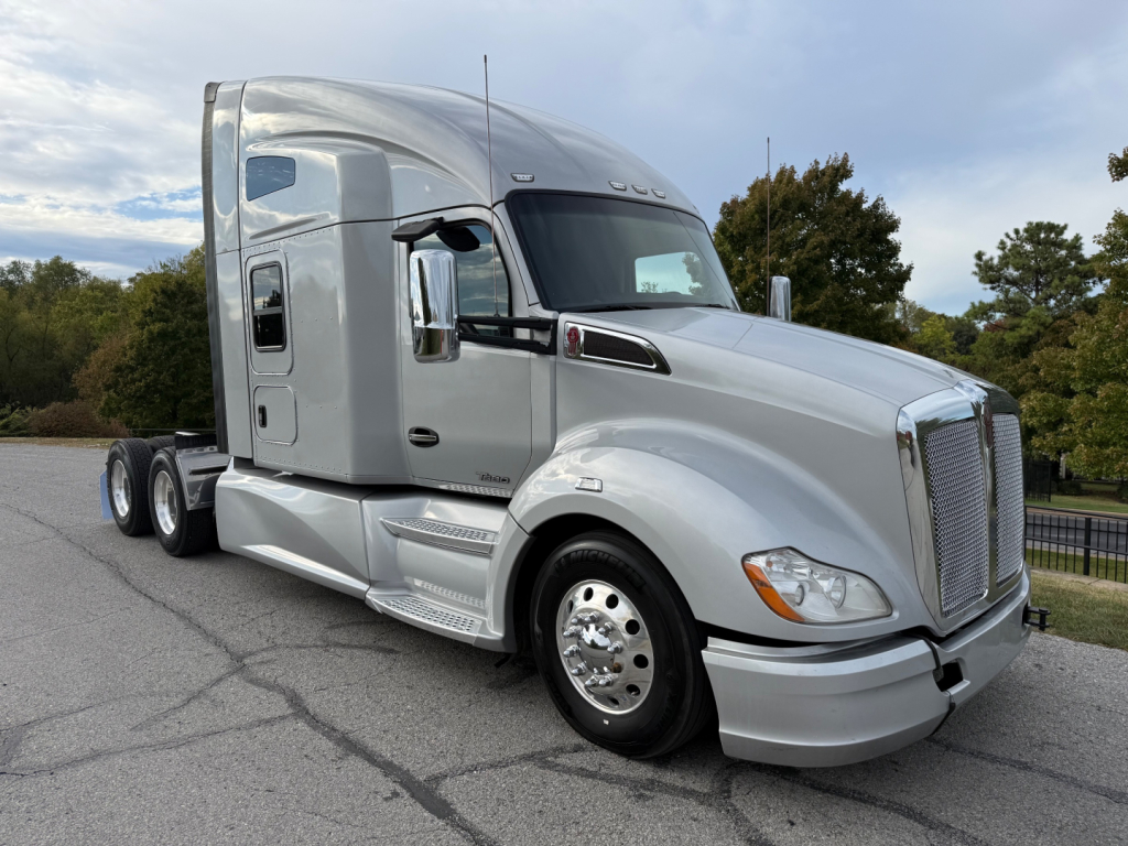 Kenworth T680 semi truck in silver, side view showing cab, chrome mirrors, aerodynamic fairings, and dual rear axles.