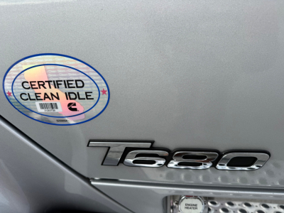 Kenworth T680 badge on door with Certified Clean Idle sticker visible.