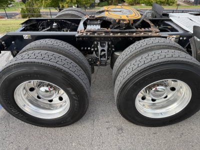 Kenworth T680 chassis with dual rear axles and wheel rims visible, showing tires and suspension components under the cab.