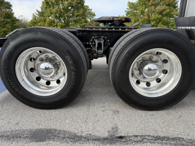 Kenworth T680 dual rear wheels tractor truck chassis showing polished steel rims and tires, undercarriage components, and frame rails.