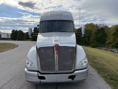 Kenworth T680 tractor front view showing dual chrome grille, large windshield, and cab with aerodynamic hood; headlights and bumper visible.