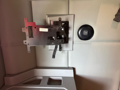 Incorrectly positioned mounting bracket and panel in a Kenworth T680 interior dash area showing a metal plate with cutouts and a small label, mounted near a circular knob.