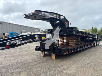 Trailer showing a black Eager Beaver 35Gsl-S lowboy with gooseneck crane, stacked steel deck sections, and white Eager Beaver logo on the side.