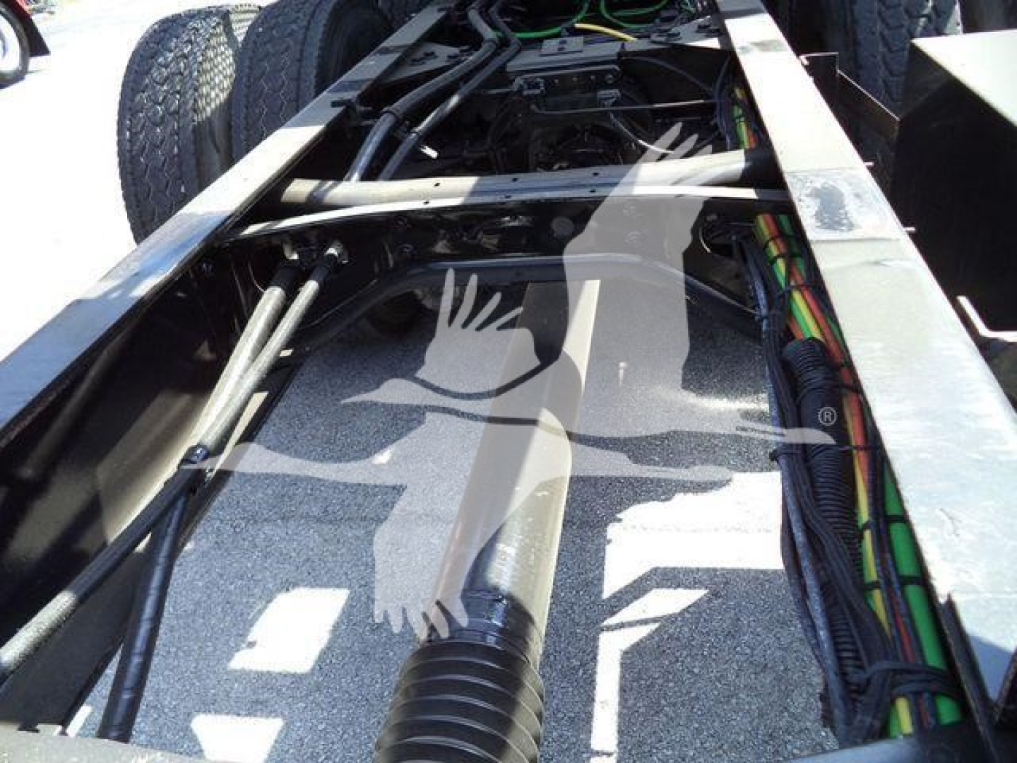 Truck chassis with hydraulic lines and dual tires visible, cabling and frame rails in view, 2016 International Workstar part of rollback truck.