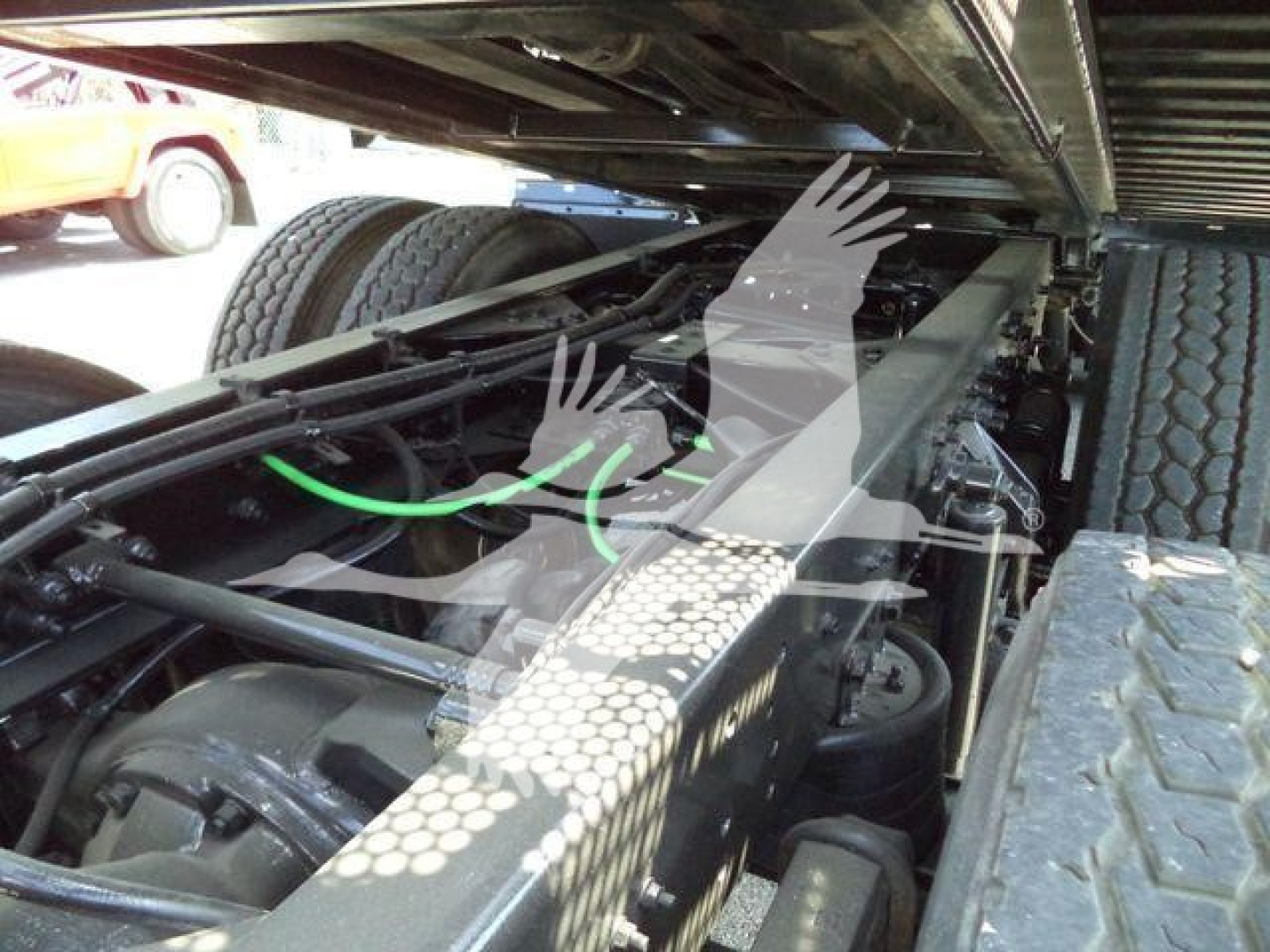 Truck chassis undercarriage showing heavy-duty frame with green hose and suspension components.