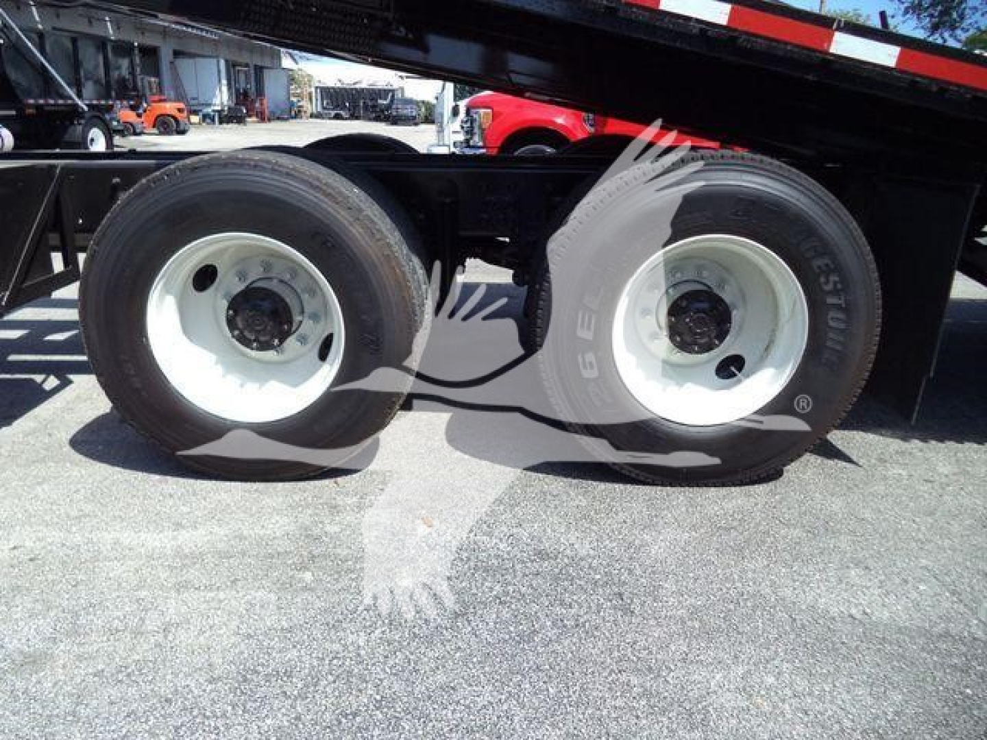Dual rear wheels of a heavy truck trailer showing white steel rims and black tires in a rollback yard.