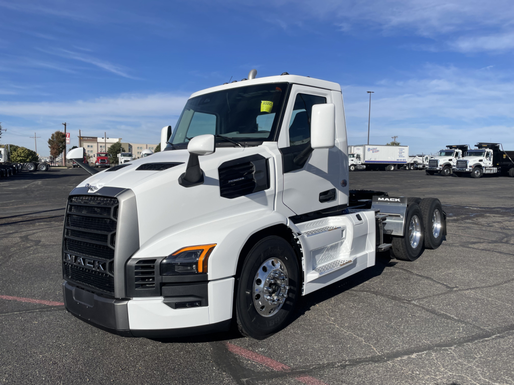 Mack PR64T tractor-trailer truck in white, front-left view, with black grille and chrome wheels; visible side steps and dual rear axles.