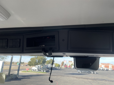 Dashboard area of a 2026 Mack PR64T cab showing overhead compartments and a hanging cord with a screen compartment.