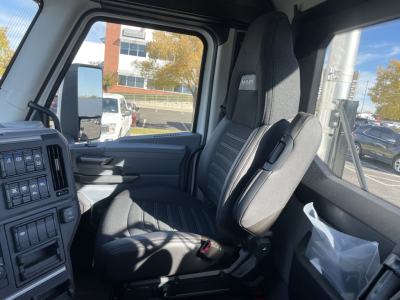 Mack PR64T truck cab interior showing driver seat and steering area with black seat upholstery.