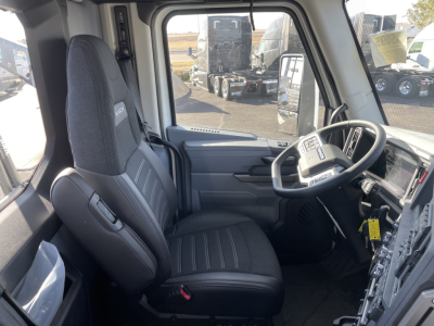 Interior cab view of a 2026 Mack PR64T truck showing driver seat, steering wheel with controls, dashboard, and doorway.