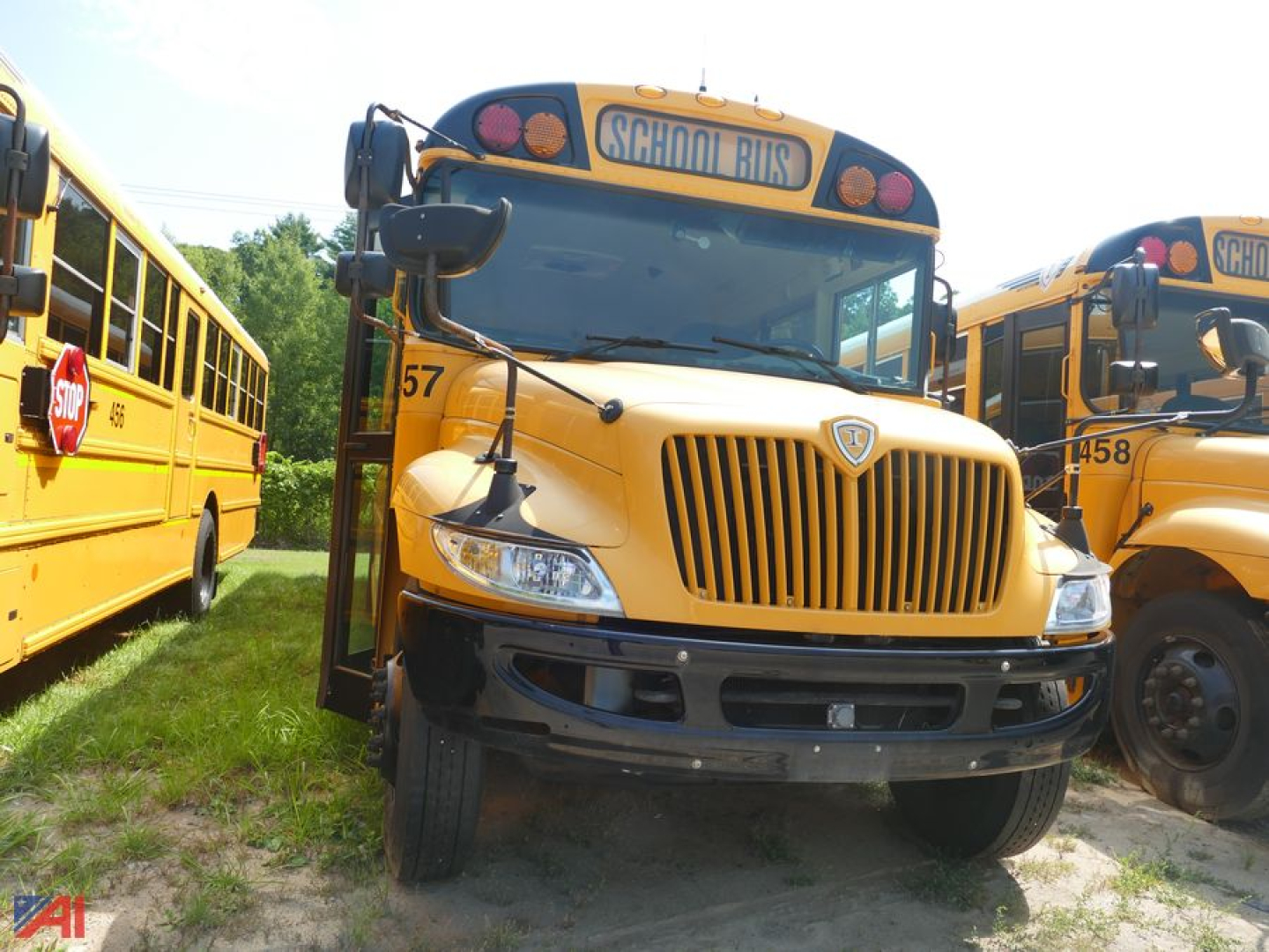 School bus front view showing 2019 International CE 3000 with yellow body and grille, 'SCHOOL BUSES' sign on top, other buses in background.