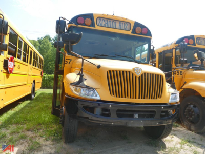 School bus front view showing 2019 International CE 3000 with yellow body and grille, 'SCHOOL BUSES' sign on top, other buses in background.