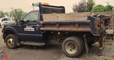 Ford F-350 Super Duty XL dump truck with V-plow, side text reading Village of Liverpool, DPW-Public Works, bed and plow hardware visible.