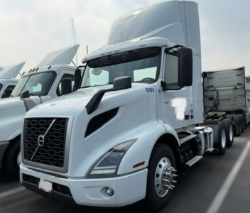 Volvo VNR64T300 tractor unit with sleeper cab, white paint, front grille, and dual rear axles in a parking lot.