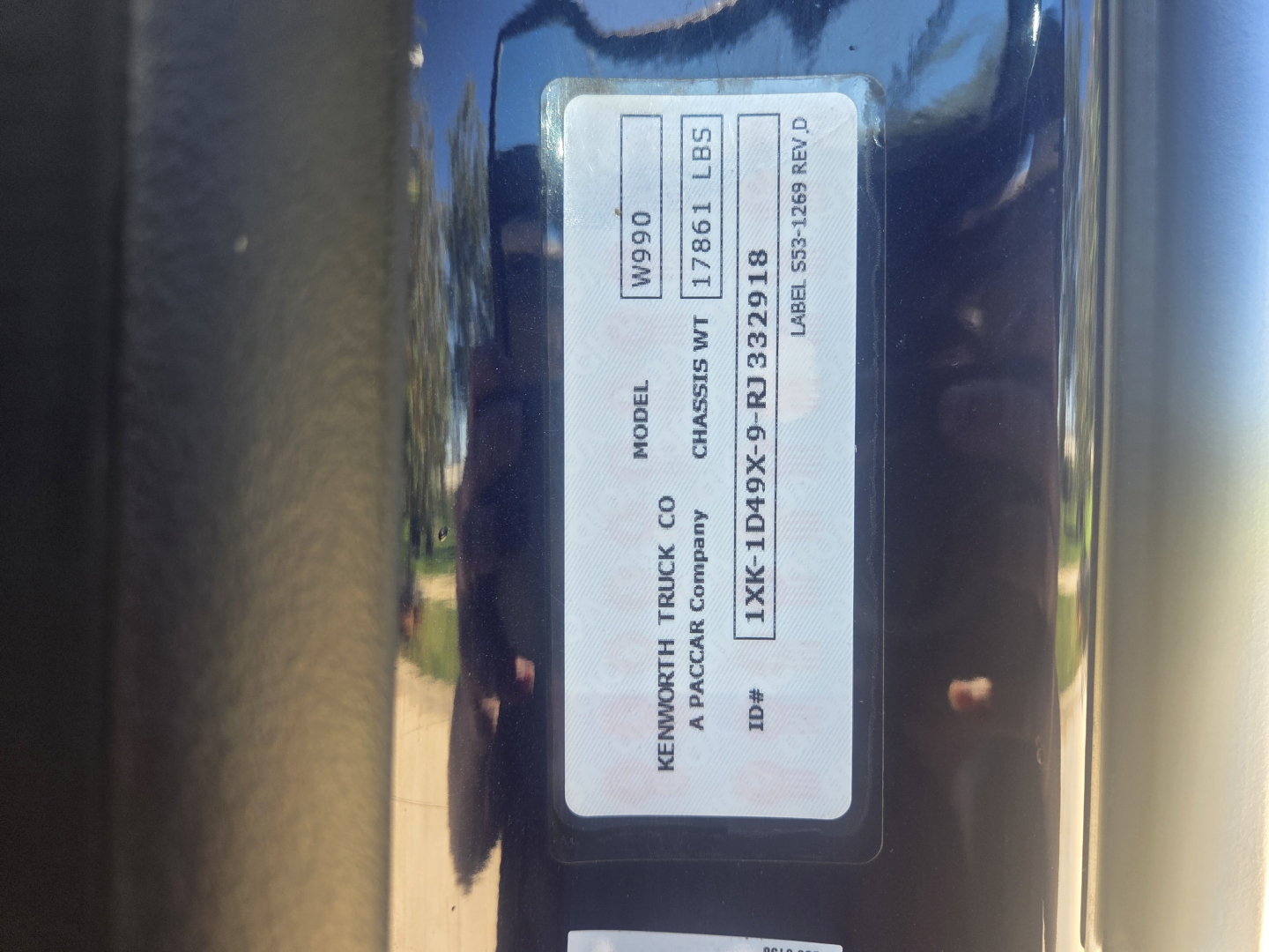Kenworth W990 door jamb label showing model W990, chassis wt 1786 lbs, serial details, and vehicle identification numbers.
