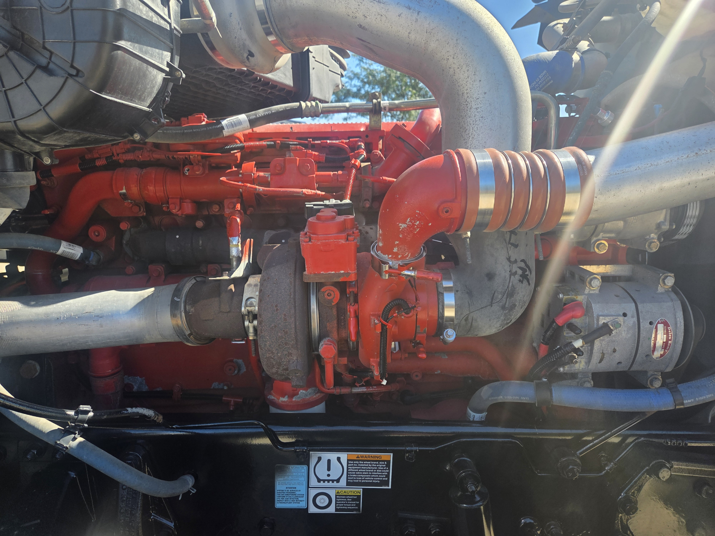 Kenworth engine bay showing red engine block, turbo pipes, and hoses in high detail.