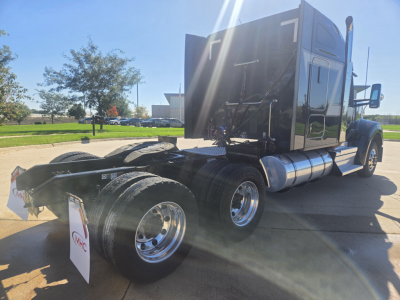 Kenworth W990 truck rear view showing dual rear axles and sleeper cab with shiny chrome fuel tanks