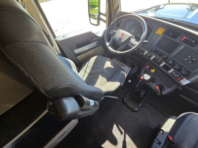 Kenworth W990 interior view of driver and passenger seats with steering wheel, dashboard, and gear shifter.