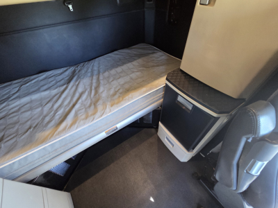 Interior of a Kenworth W990 sleeper cab showing a bed platform and storage cabinet; no visible text on components.