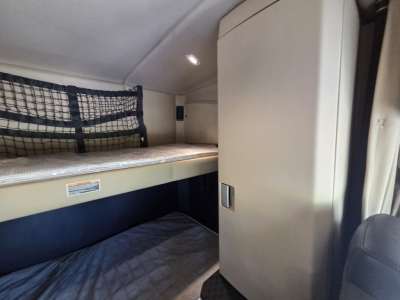 Kenworth W990 sleeper cab interior showing bunk bed and storage cabinet.