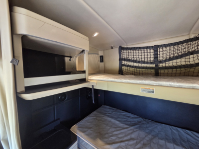Kenworth W990 sleeper cab interior showing upper bunk and storage cabinet with netted cargo pocket.
