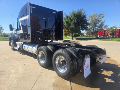 Kenworth W990 tractor rear/side view showing dual rear axles, fuel tanks, and black sleeper cab. Visible text includes branding on white mudflaps and general truck silhouette.
