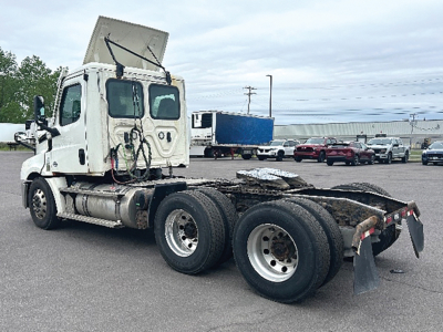 Truck chassis of a Freightliner Cascadia126 tractor showing exposed frame and rear wheel axles with fifth wheel mount.