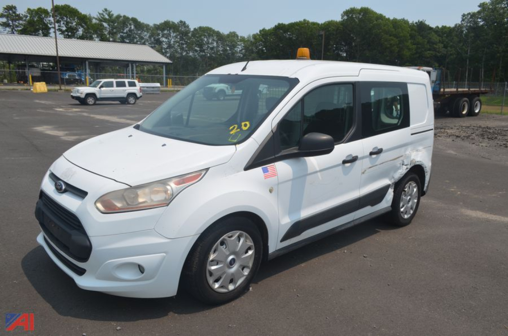 Ford Transit Connect minivan in a parking lot showing side and front view with roof marker lights and US flag sticker.