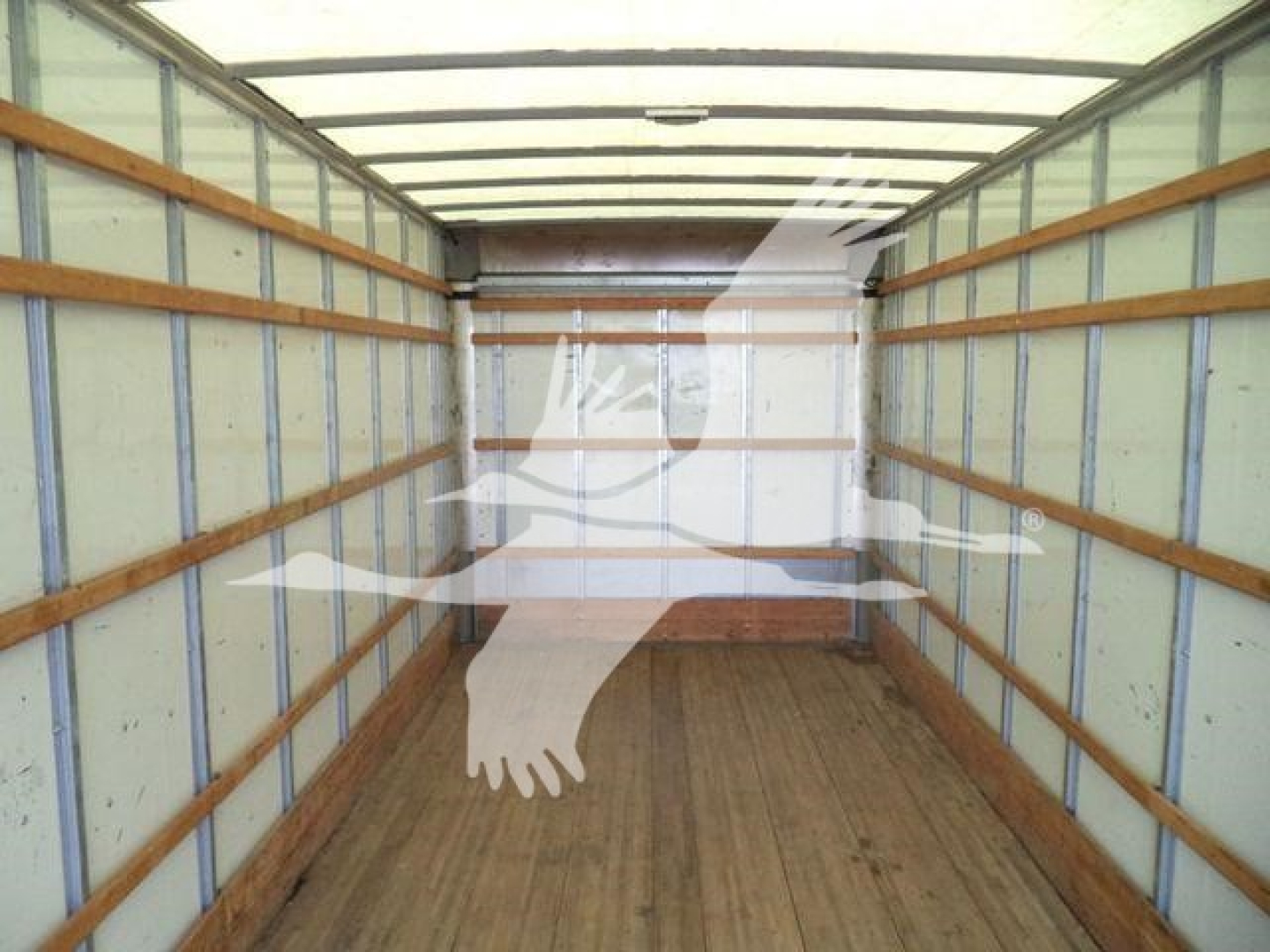 Interior of a box truck cargo area with wooden rails and light-green walls, empty.