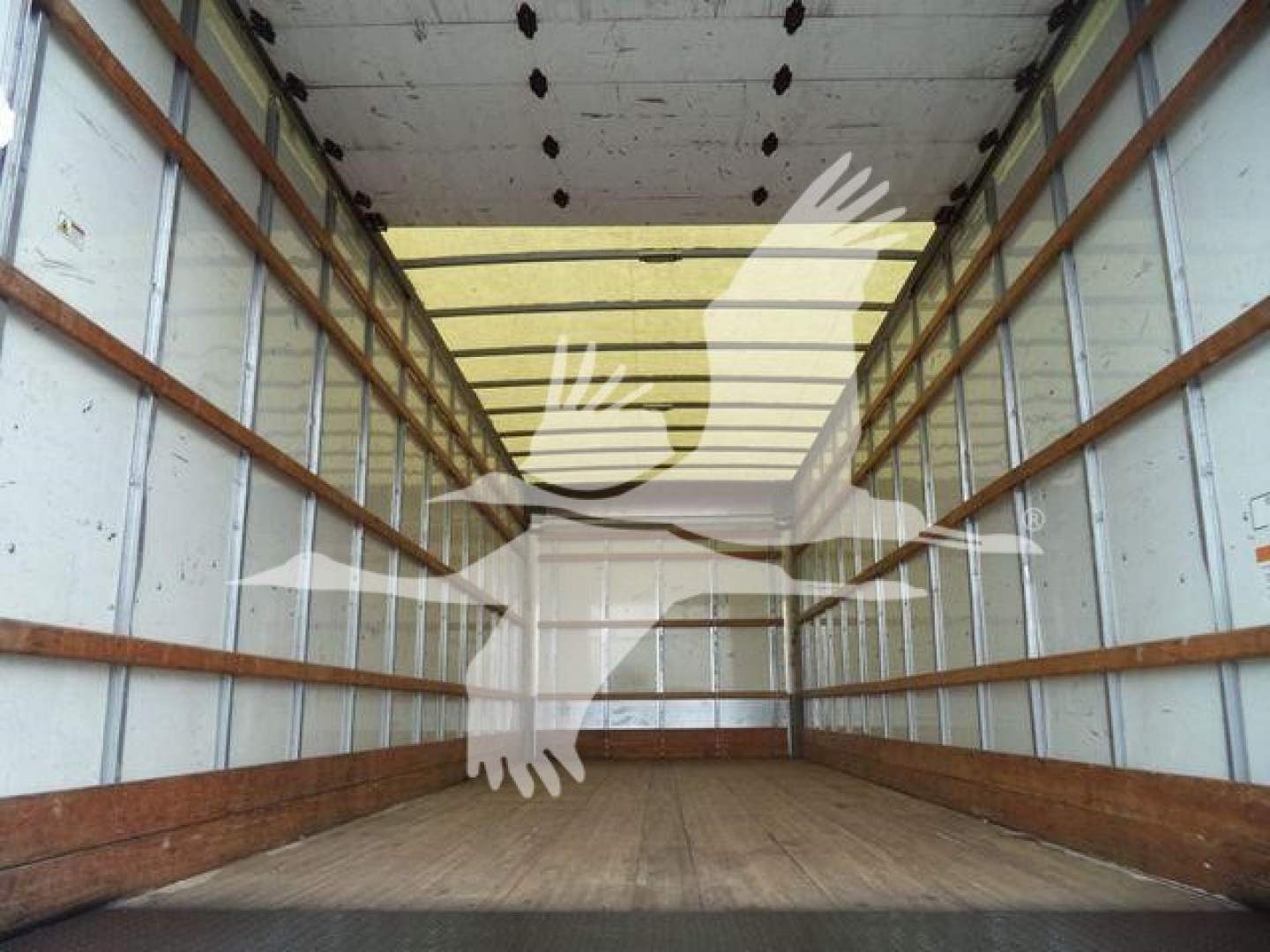 Interior cargo area of a box truck showing unloaded empty wooden side rails and metal walls