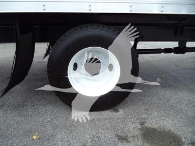 Truck wheel close-up showing white steel wheel and tire under a box truck; undercarriage and frame visible.