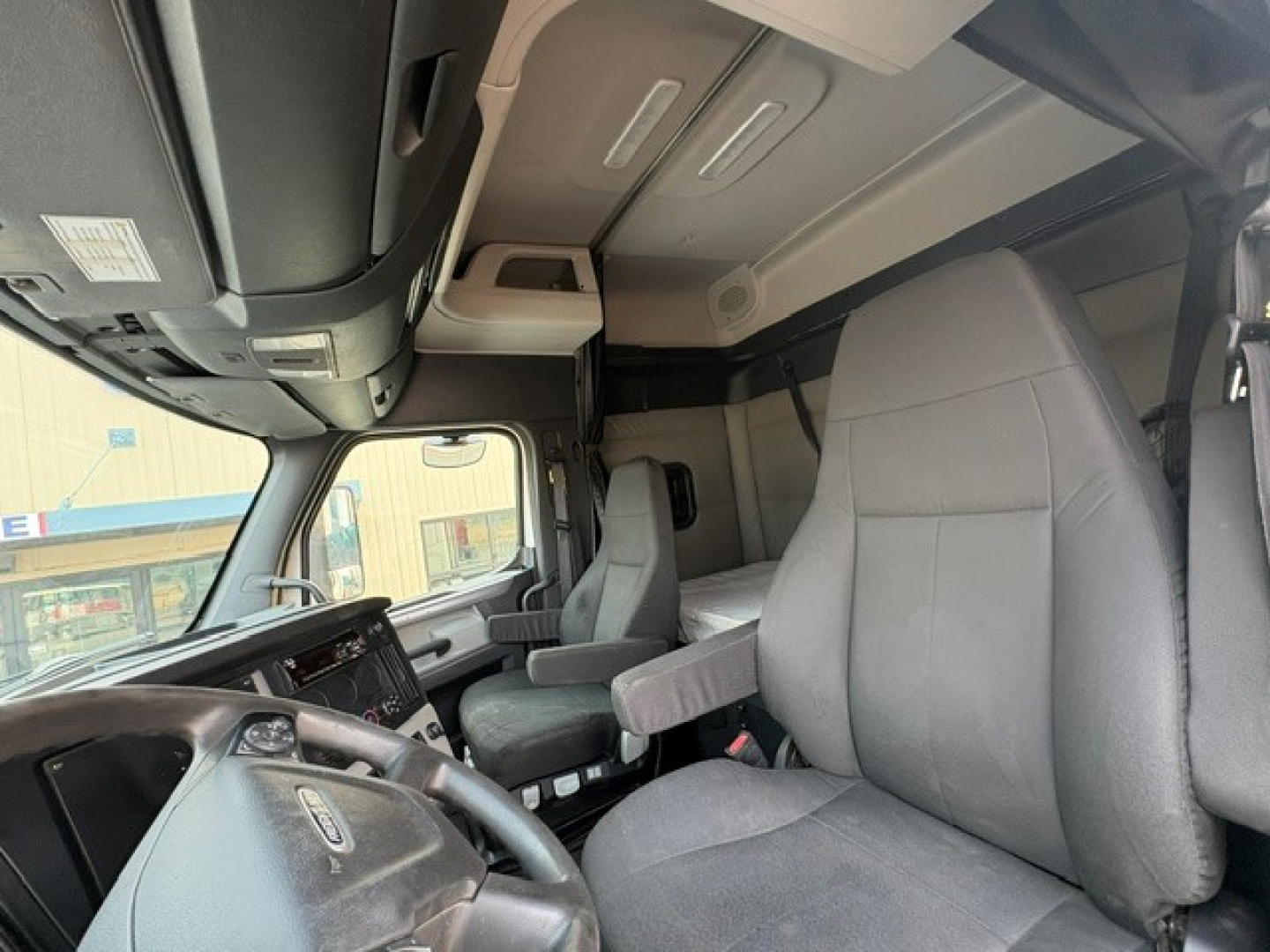 cab interior of a 2020 Freightliner Cascadia 126 truck showing driver seat, steering wheel, dashboard, and overhead storage