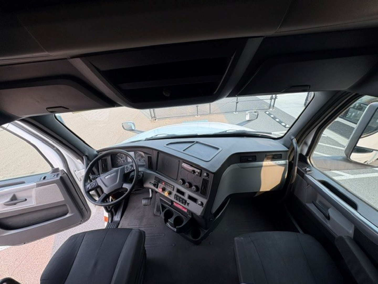 Cab interior of a Freightliner Cascadia 126 truck, driver seat visible, dashboard with steering wheel, center console, and windows; text not legible due to image resolution.