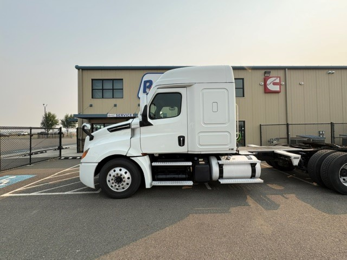 Freightliner Cascadia 126 tractor in side view showing cab, side fuel tanks and bumper with VIN plate visible.