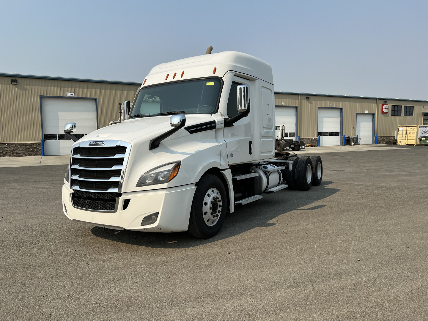 Freightliner Cascadia 126 truck in a lot showing front and side view with white cab and sleeper