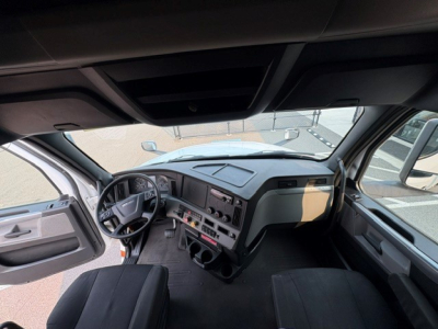 Cab interior of a Freightliner Cascadia 126 truck, driver seat visible, dashboard with steering wheel, center console, and windows; text not legible due to image resolution.