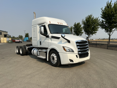 Freightliner Cascadia 126 tractor cab in white, front-side view showing sleeper cab, aerodynamic mirrors, and dual rear axles.