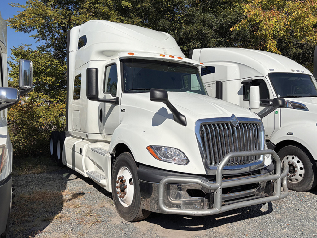 2019 International LT625 truck in white, front view with grille guard, parked among other trucks.