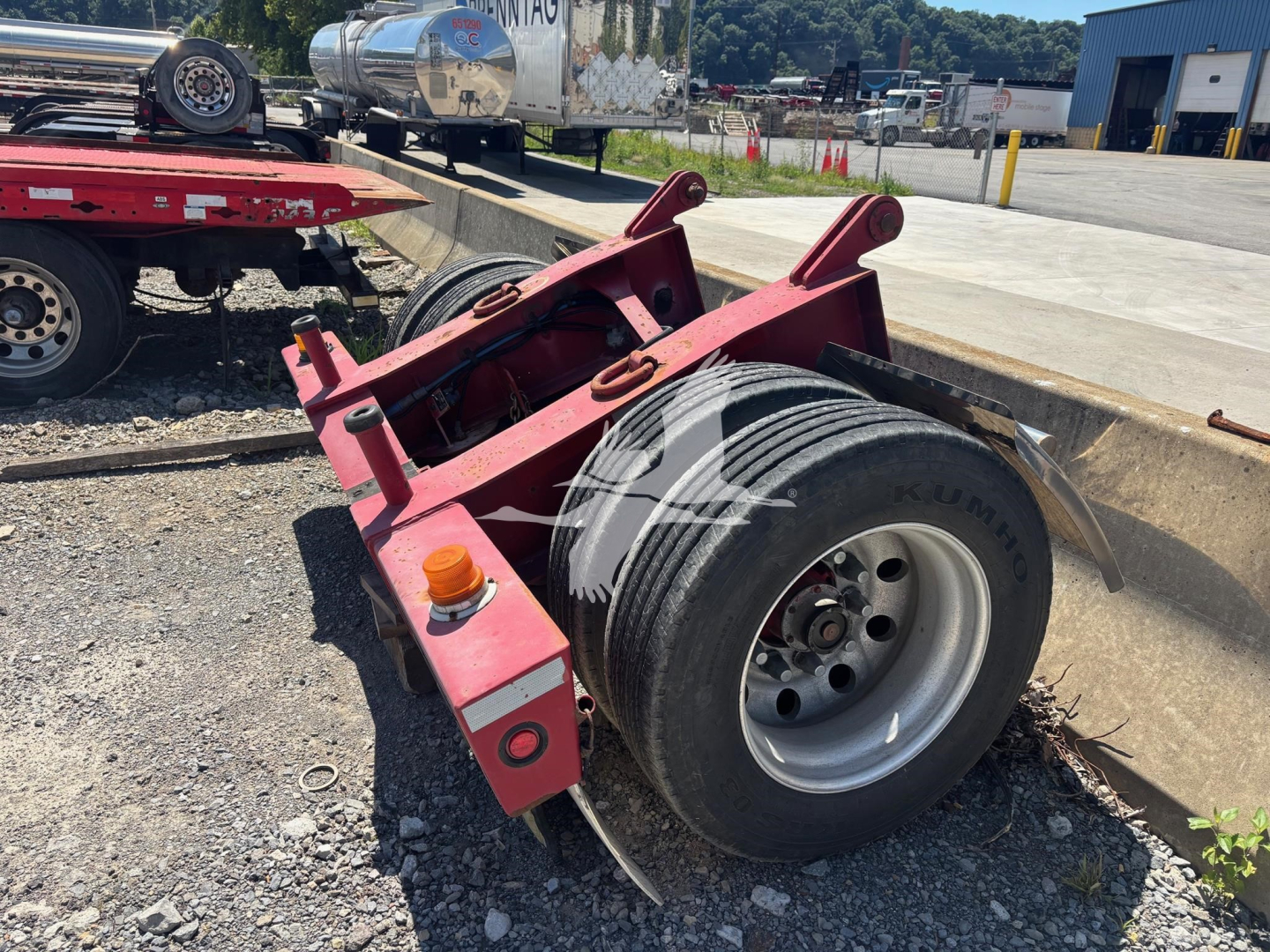 Fontaine flip trailer dolly wheel assembly with red frame and single large tire, parking lot background, caster/axle mounting points visible.
