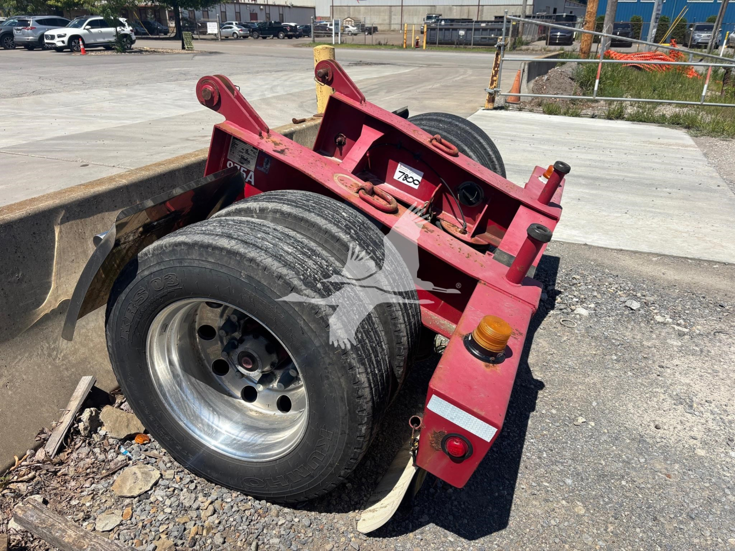 Fontaine flip trailer dolly showing dual rear axles with large tires, red frame, hydraulic components, and warning/label stickers.