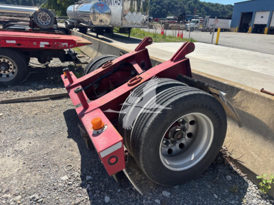 Fontaine flip trailer dolly wheel assembly with red frame and single large tire, parking lot background, caster/axle mounting points visible.