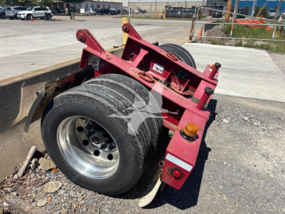 Fontaine flip trailer dolly showing dual rear axles with large tires, red frame, hydraulic components, and warning/label stickers.