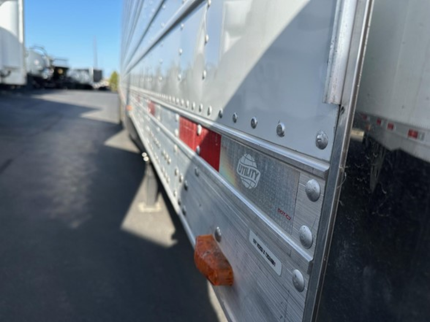 Trailer side view showing riveted metal wall and reflective reflectors on a 2026 Utility 3000R reefer trailer.