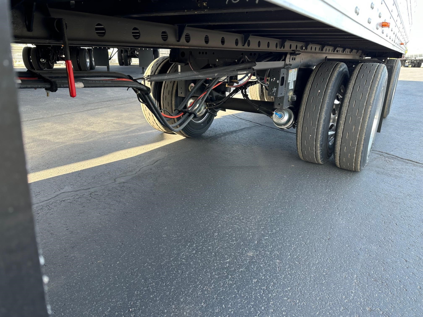 Trailer undercarriage showing dual rear axles and wheel assemblies of a new 2026 Utility 3000R reefer trailer with visible hydraulic lines and suspension components.