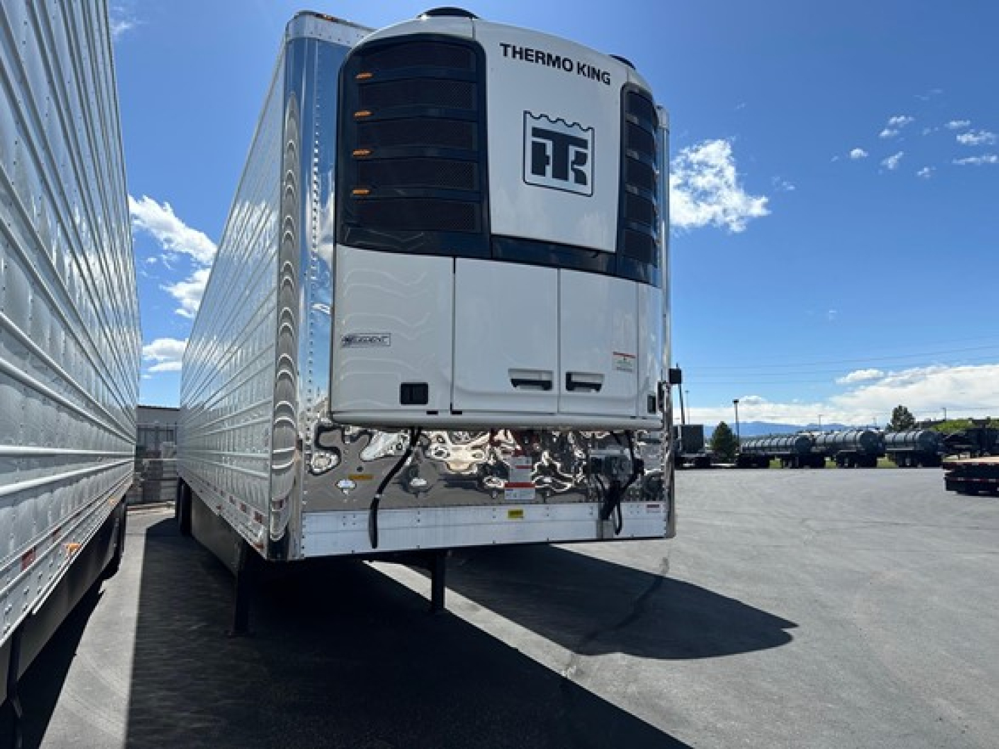 Front view of a Thermo King refrigerated trailer unit mounted on a new Utility 3000R trailer with white body, black cooling unit, and chrome front bumper.