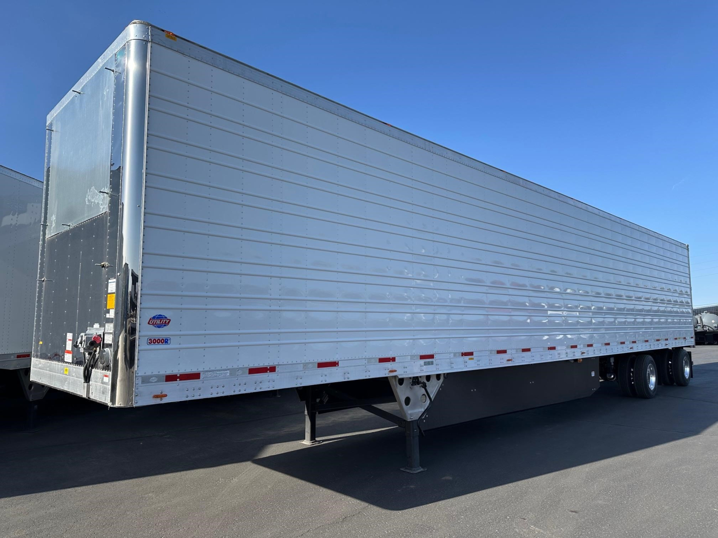 Trailer side view of a 2026 Utility 3000R reefer trailer showing aluminum exterior and reflective red/white side markers.