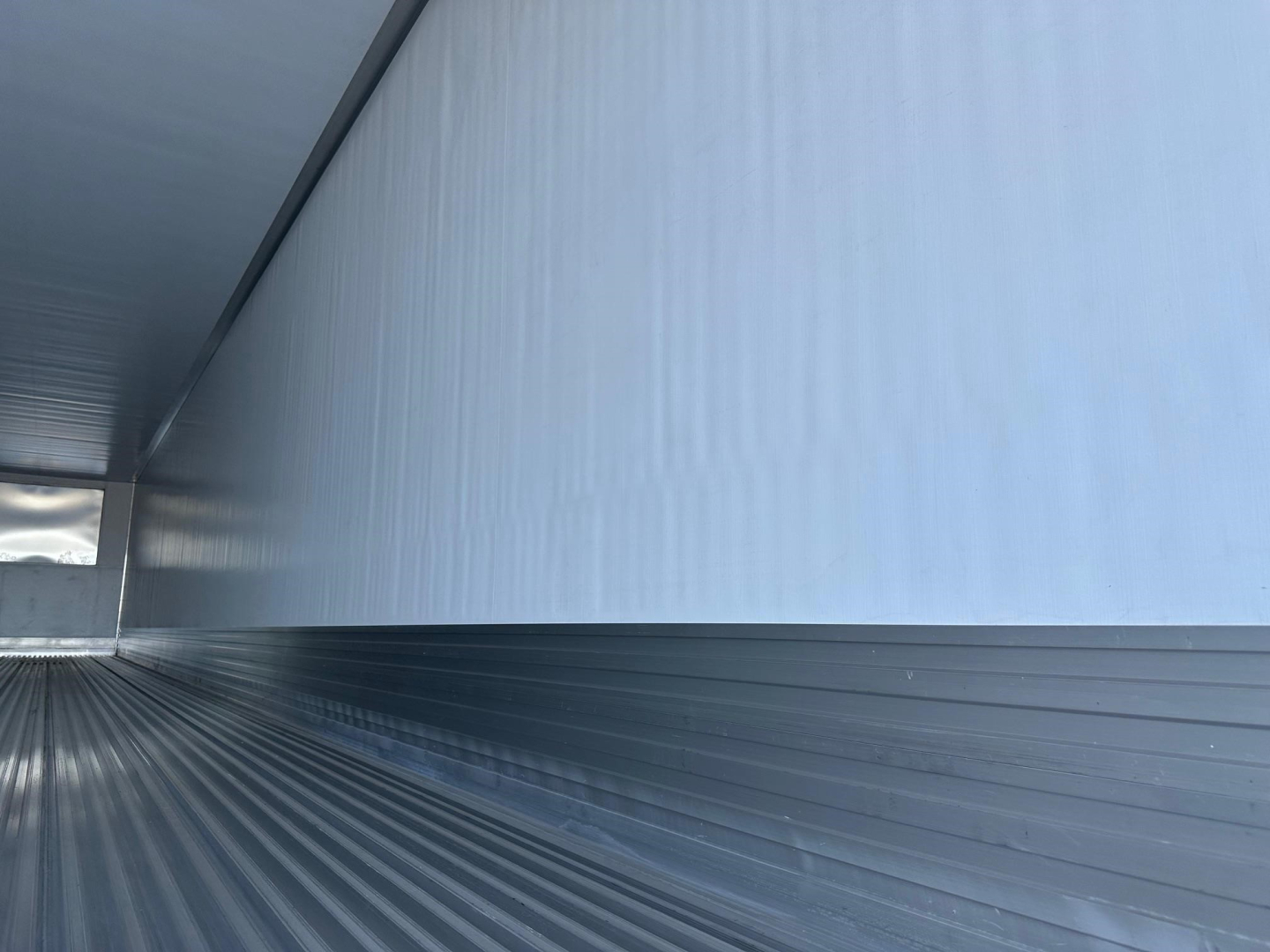 Trailer interior showing insulated white wall and ribbed metal floor in a 2026 Utility 3000R reefer trailer.