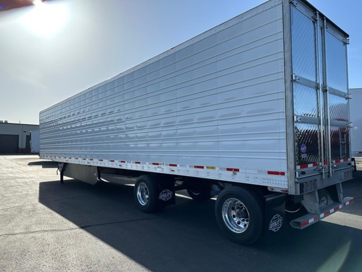Utility 3000R trailer side view showing aluminum cargo area and rear doors, tandem axle wheels, and reflectiveSafety tape.