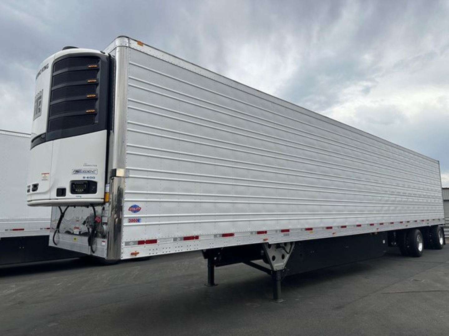 Utility 3000R trailer side view showing reefer unit at front with external refrigeration unit and silver ribbed side panels.